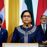 세계사 속 여성 지도자 - A dignified Bengali woman political leader standing confidently at a podium during a diplomatic summ...